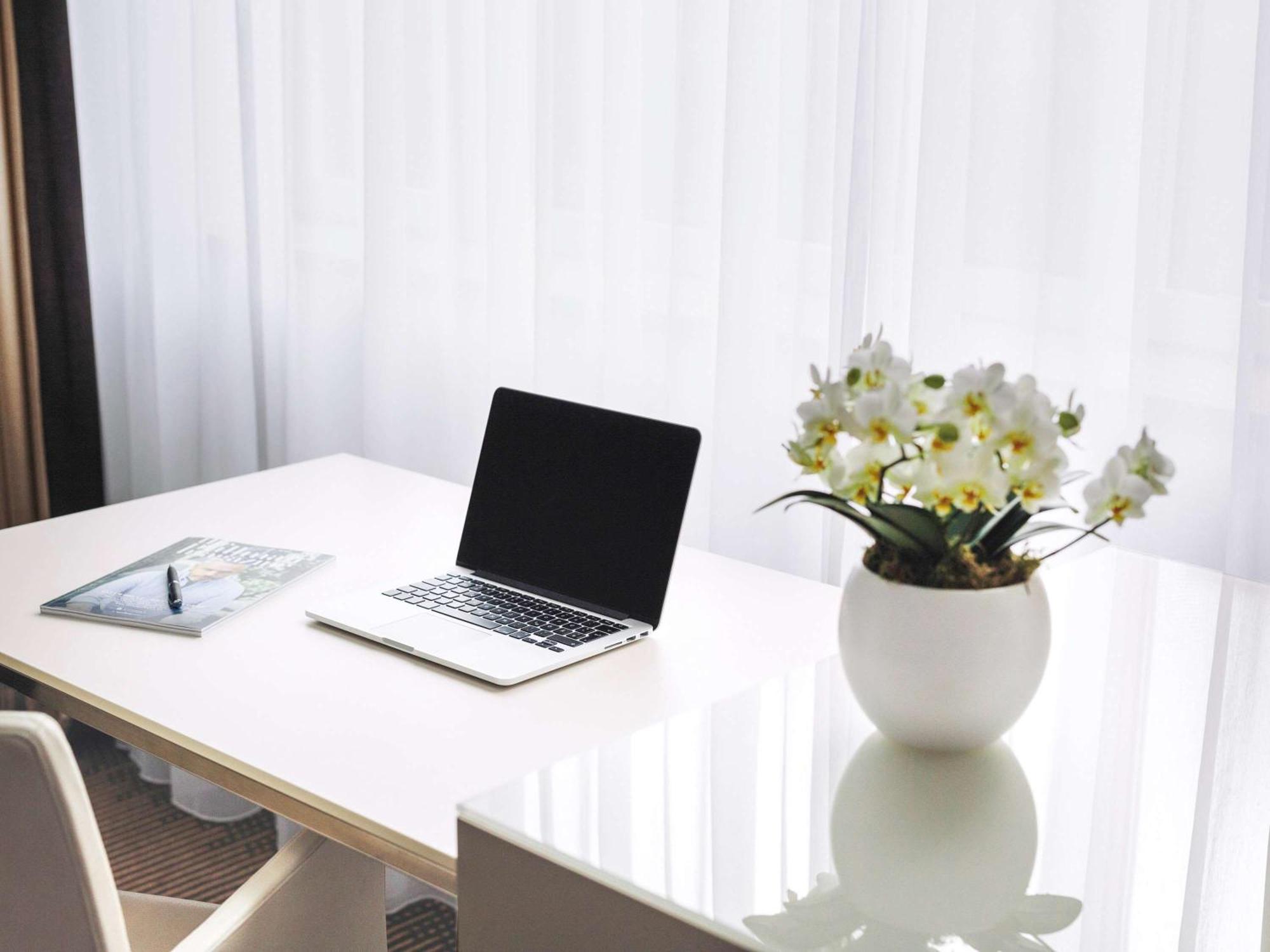โรงแรมพูลแมน เบอลิน ชไวเซอร์ฮอฟ เบอร์ลิน ภายนอก รูปภาพ A desk with a laptop and a vase of flowers